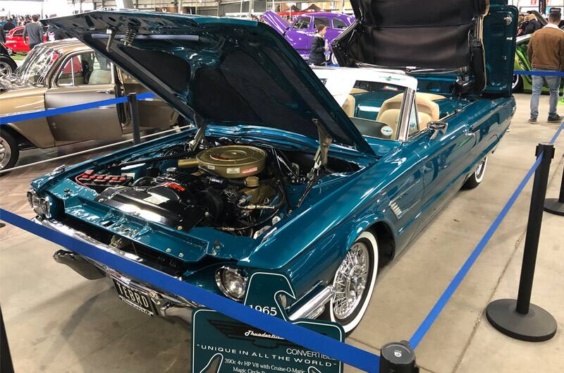 Front of teal Thunderbird with roof down and hood and trunk open on display at car show