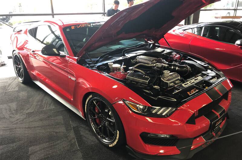 Front profile of red Mustang with hood open on display