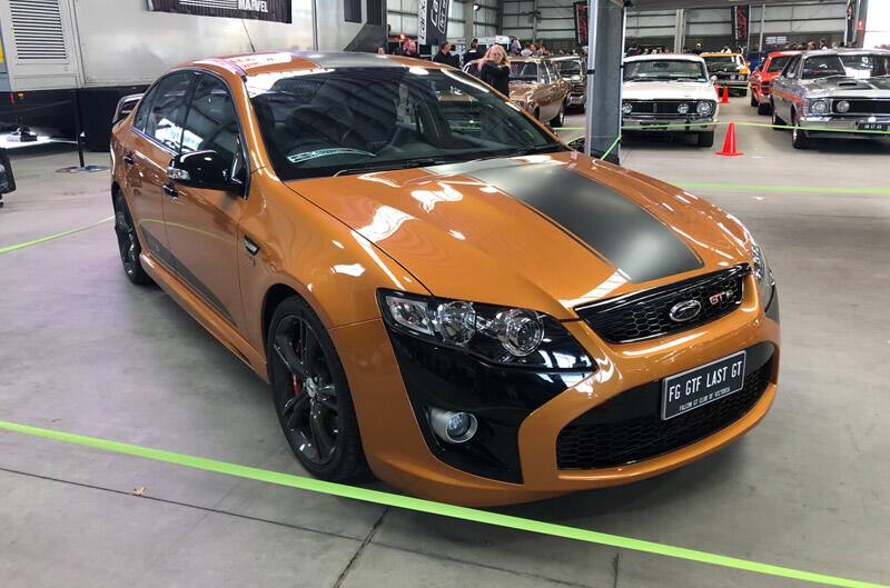 Front profile of a orange GT with black stripe on display at car show