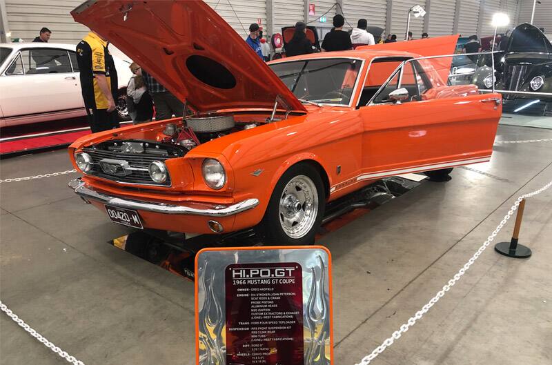 Front profile of orange Mustang GT Coupe wit hood and trunk open and driver door open on display at car show