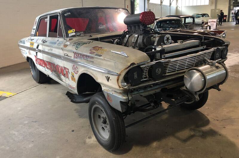 Front of a dirty white Thunderbolt with hood off parked in garage