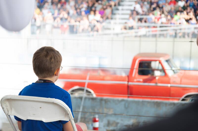 Back of Patch Hurty sitting in the stands looking at a Ford truck on the track