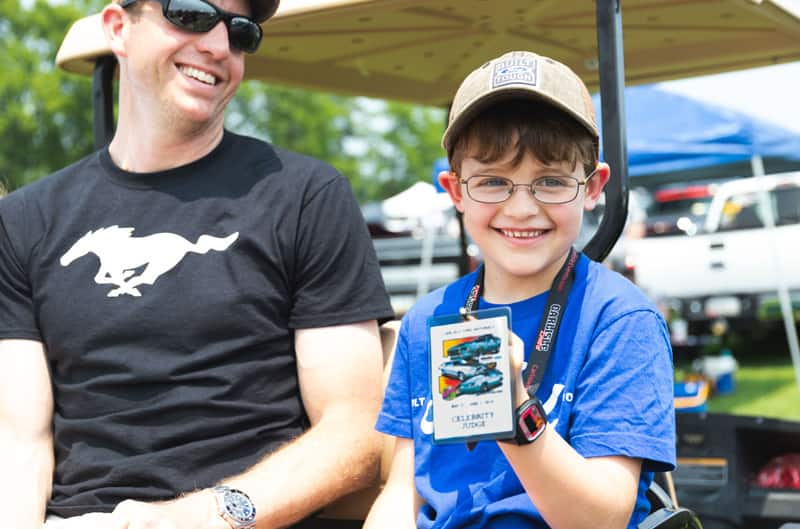 Patch Hurty holding up his celebrity pass sitting on the back of a golf cart