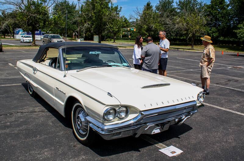 Front of white Thunderbird droptop with people behind it in parking lot