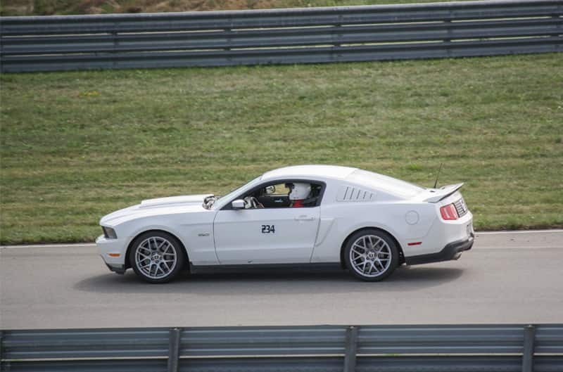 Profile of white Mustang Boss driving on road