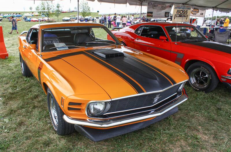 Front of orange Mustang Boss with black stripe on hood parked under tent