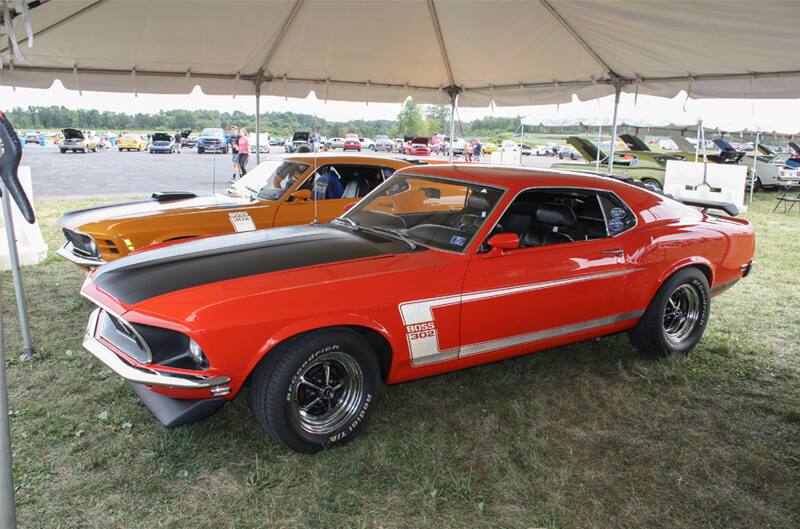 Profile of red Mustang Boss with black hood parked under tent