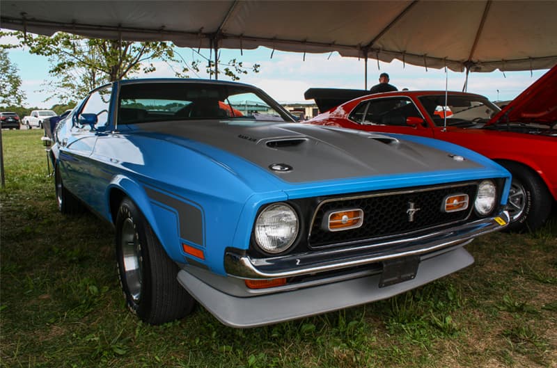 Front of blue Mustang boss with gray hood parked under tent