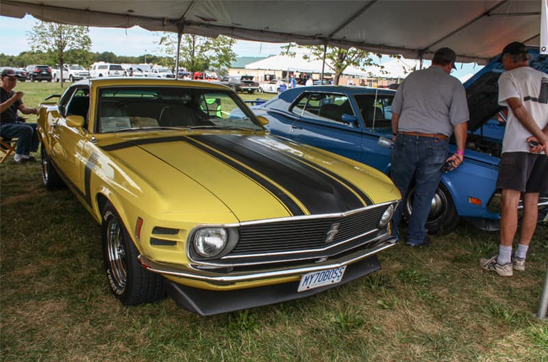 Front of yellow Mustang Boss with black stripe on hood parked under tent