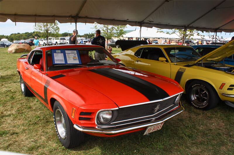 Front of red Mustang Boss with black stripe on hood parked under tent