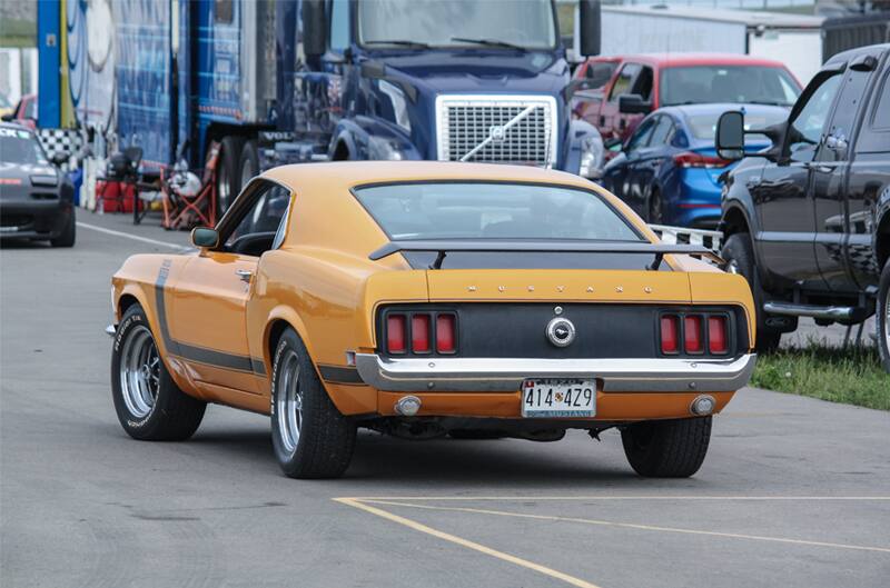 Rear of orange Mustang Boss driving in parking lot