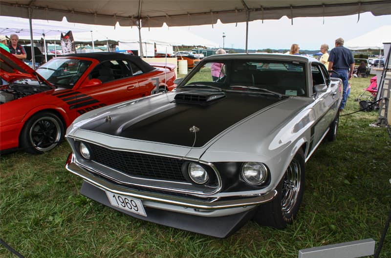 Front of silver Mustang Boss with black hood parked under tent