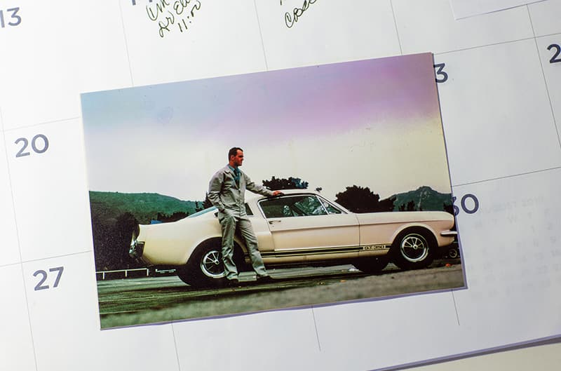 Picture of a man standing next to the profile of a white Shelby Mustang GT500 in a parking lot