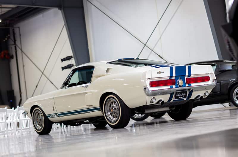 Rear profile of the white Shelby Mustang GT500 in a garage hall