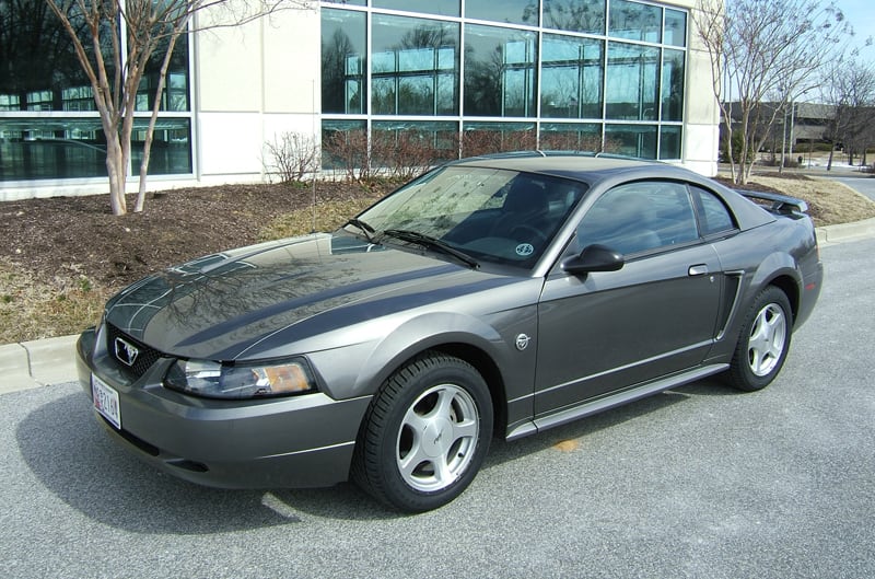 Front profile of dark gray Mustang in front of dealership