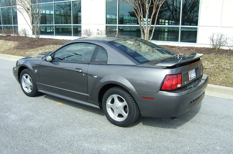 Rear profile of dark gray Mustang in front of dealership