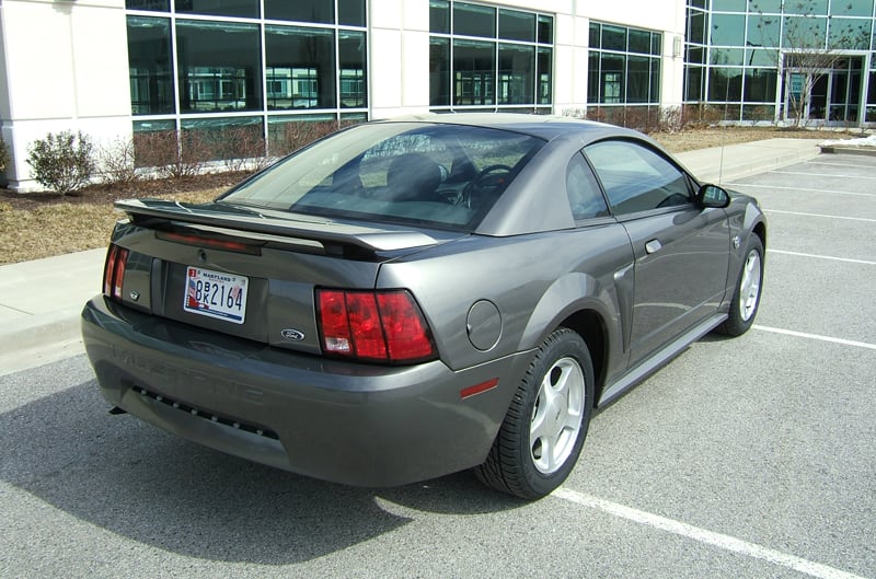 Rear profile of dark gray Mustang in front of dealership