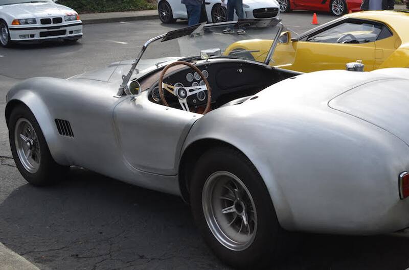 Profile of a silver Shelby Cobra droptop with roof down in parking lot