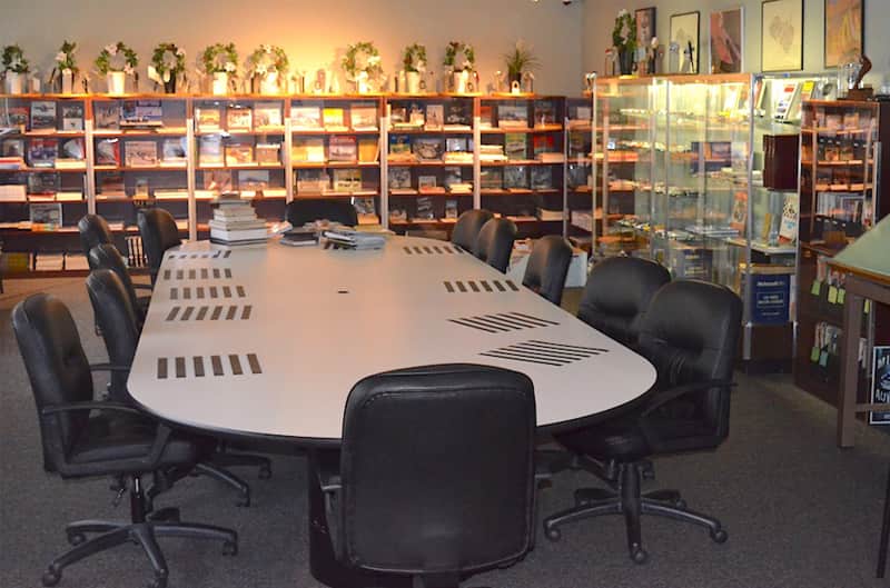 Image of an office table with chairs around it and bookshelves full of various Cobra related products