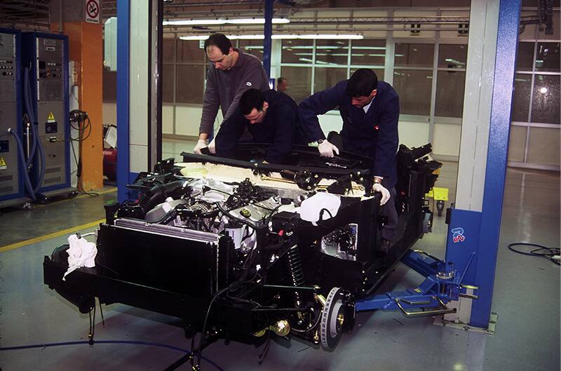 Three mechanics working on a car body