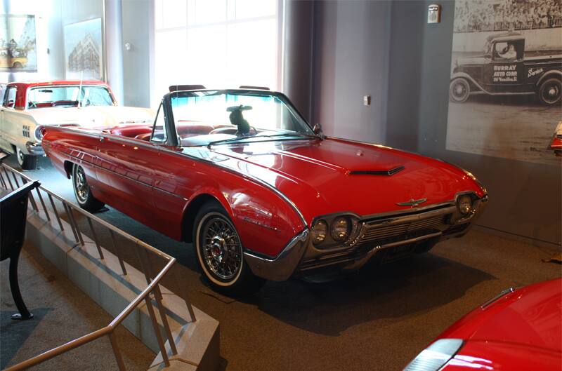 Front profile of a red Thunderbird droptop wtih roof down on display