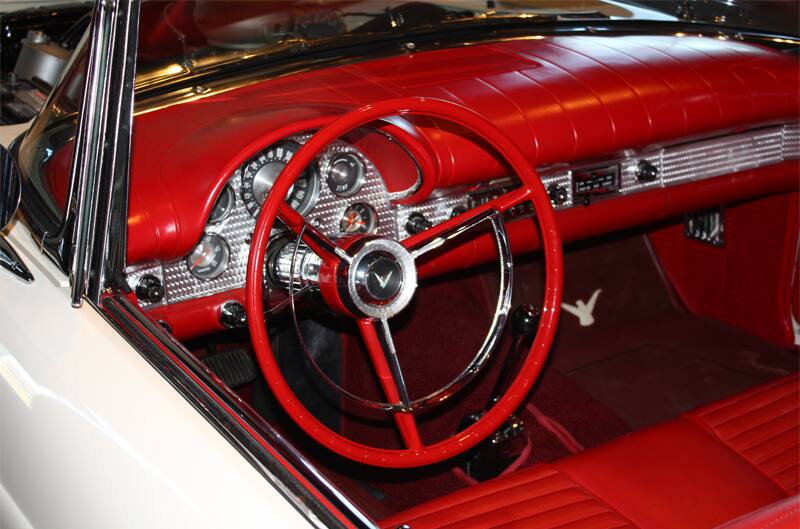 Interior close up from driver side of red steering wheel and dashboard