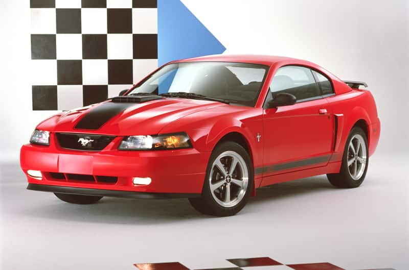 Front of red Mustang Mach 1 with black stripe on hood and side in a studio