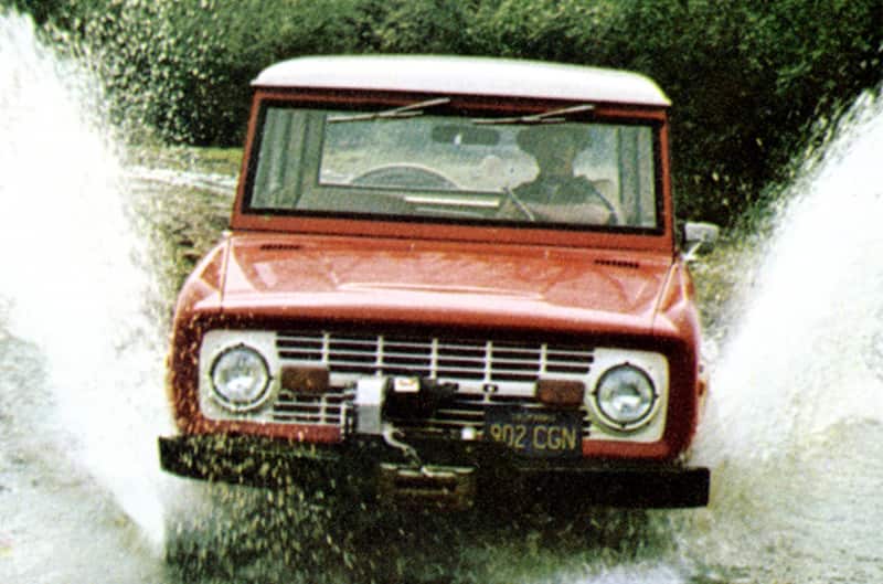 Old Bronco driving through large puddle