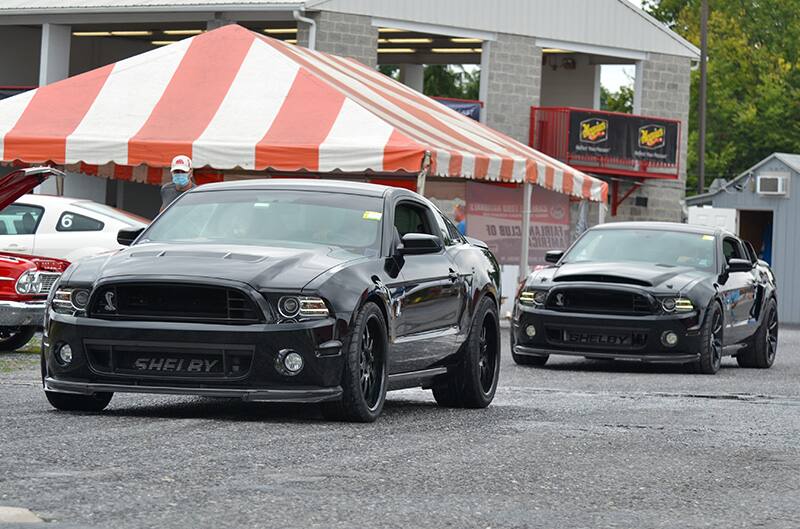 Two black Shelbys driving on the pavement