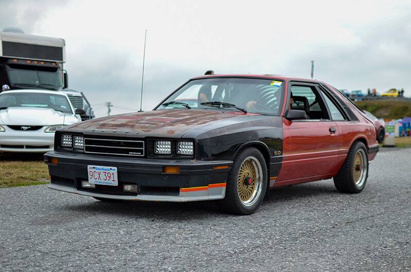 Red Capri with a black front end driving on the pavement