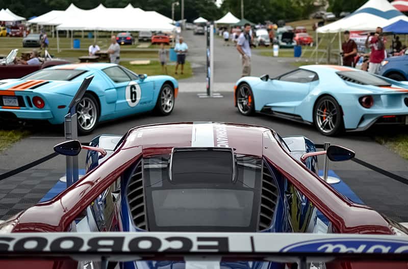 Top of a red EcoBoost GT facing two Heritage GTs facing the people and tents