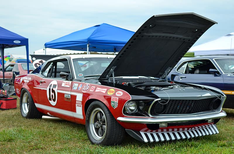 Front profile of a red Mustang Boss 302 with hood open parked on the grass