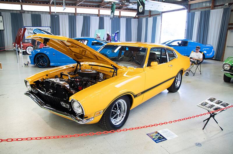 Front profile of a yellow Mustang on display in a garage