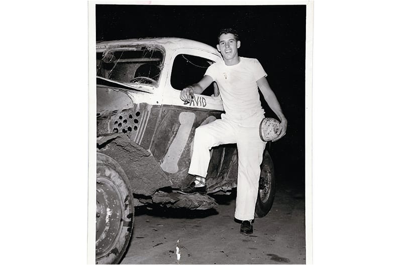 Black and white photo of David Pearson posing next to Ford race car