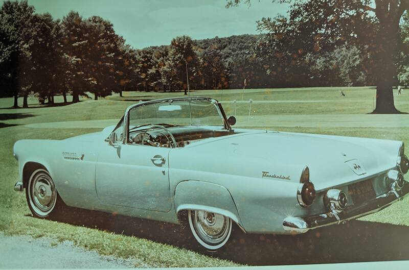 aged photo of light blue Thunderbird parked in the grass