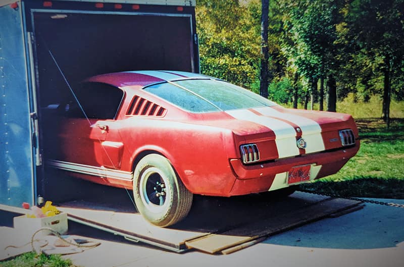 Red Mustang half out of enclosed trailer