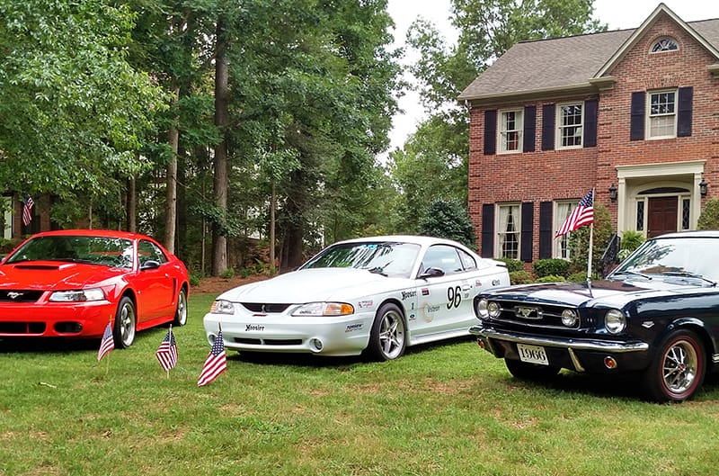 Mustangs parked on the front lawn of house on july 4th