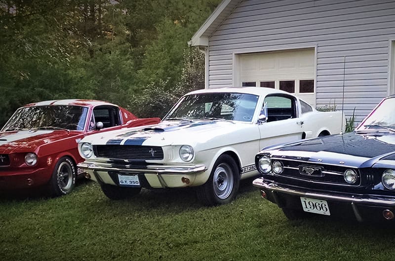 three 1960s mustangs parked by the garage