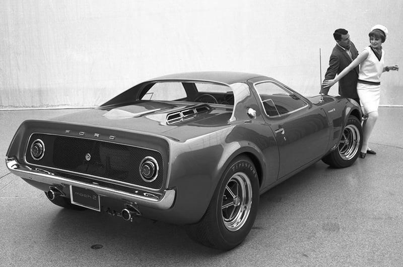 Ford Mach 2 concept in studio with couple posing behind the car