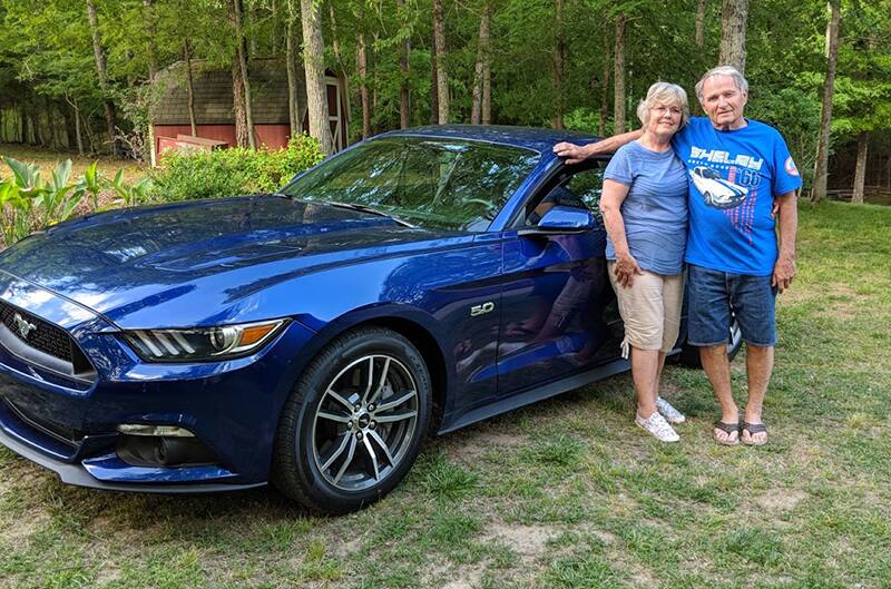 Young parents standing with their 2016 Mustang GT