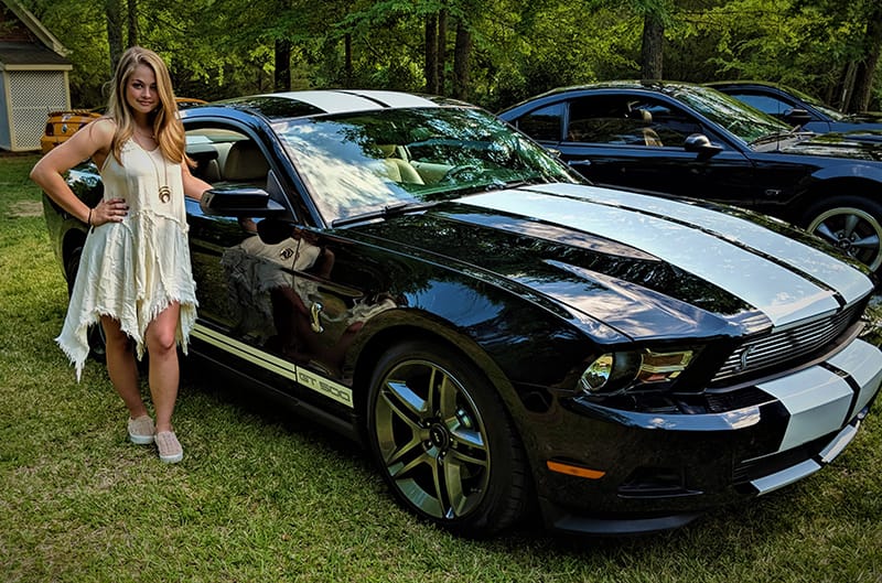 Leah standing with her Shelby Clone mustang