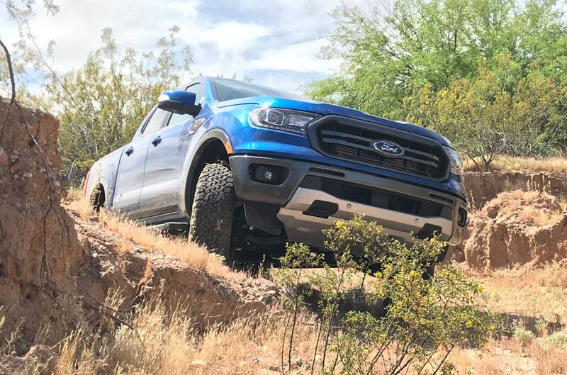 Front of blue Ranger F150 driving up a small dirt hill