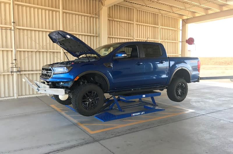 Profile of blue Ranger F150 lifted with hood up in garage