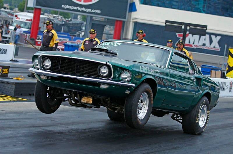 With front wheels off the track, Lance Line's green 1969 Cobra Jet Mustang races down the dragstrip