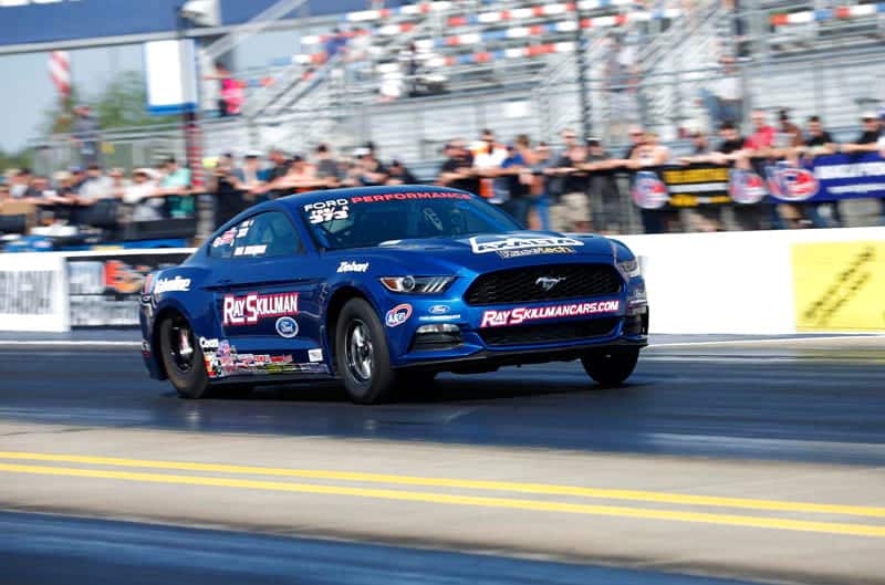 Ray Skillman's blue Cobra Jet Mustang races down dragstrip where fans can be seen