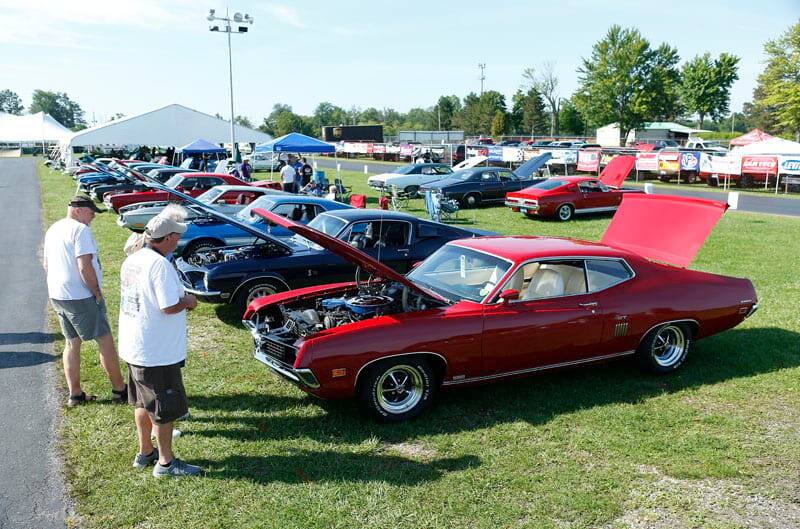 Fans admiring the Cobra Jets that are lined up on the lawn at Summit Motorsports Park