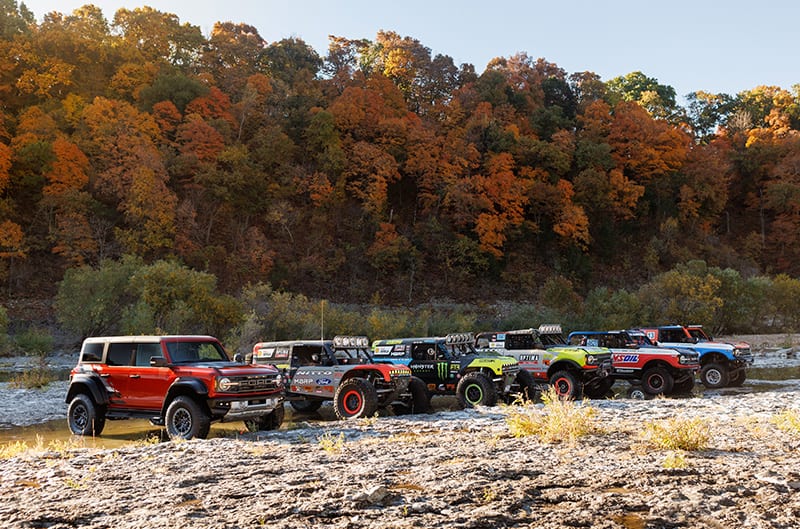 All six Ford Broncos of various series parked in fall woods setting
