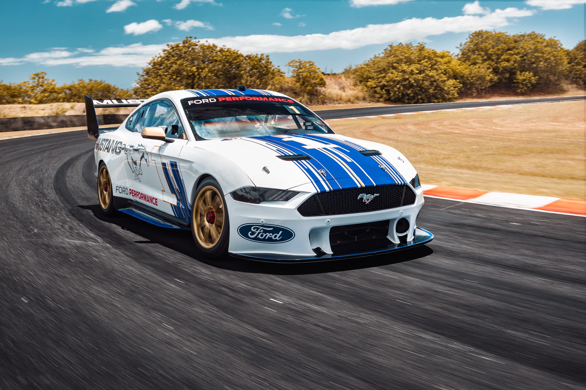 The white and blue Ford Mustang turning a corner at high speeds