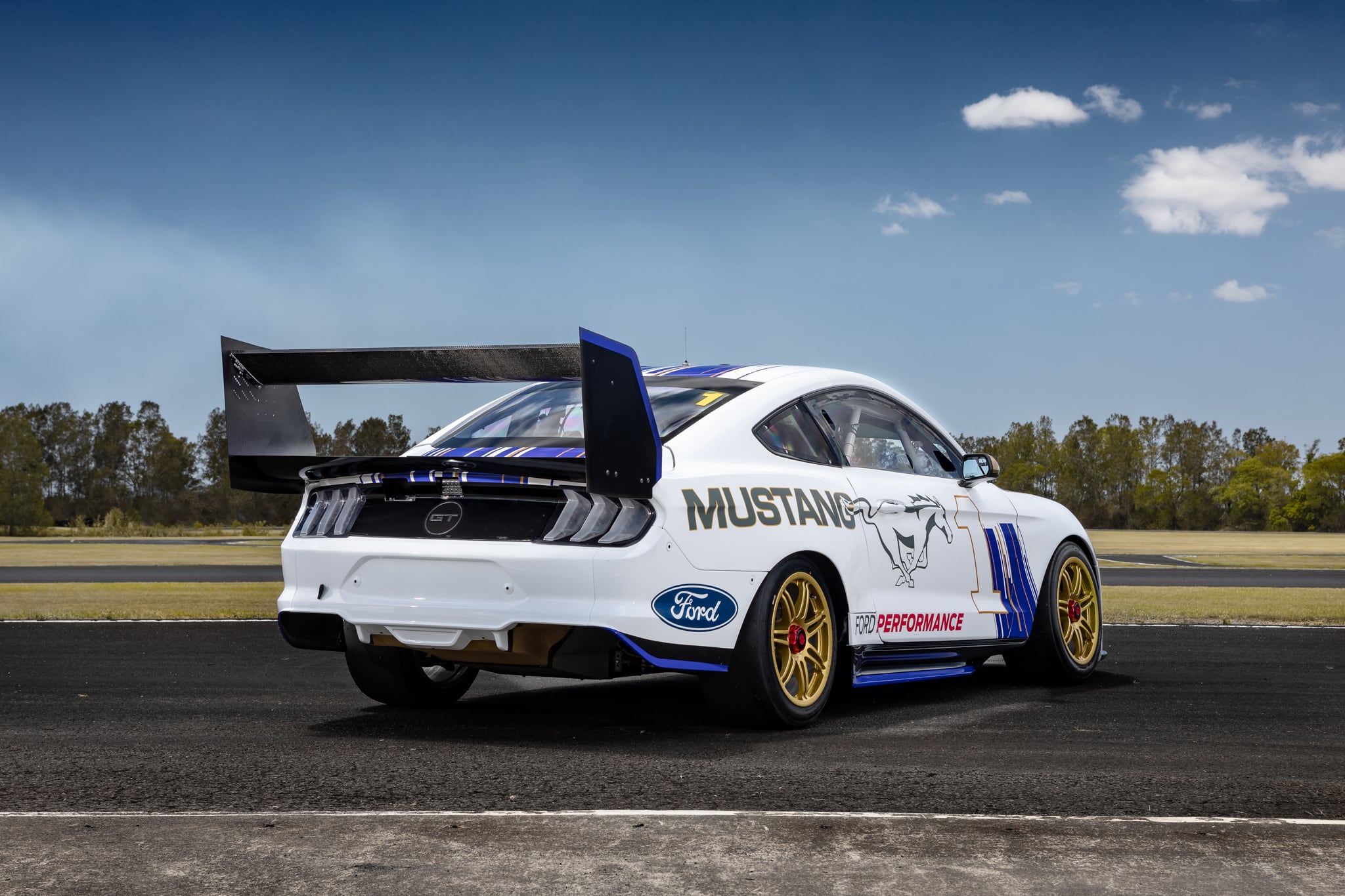 The white and blue Ford Mustang accelerating down the track