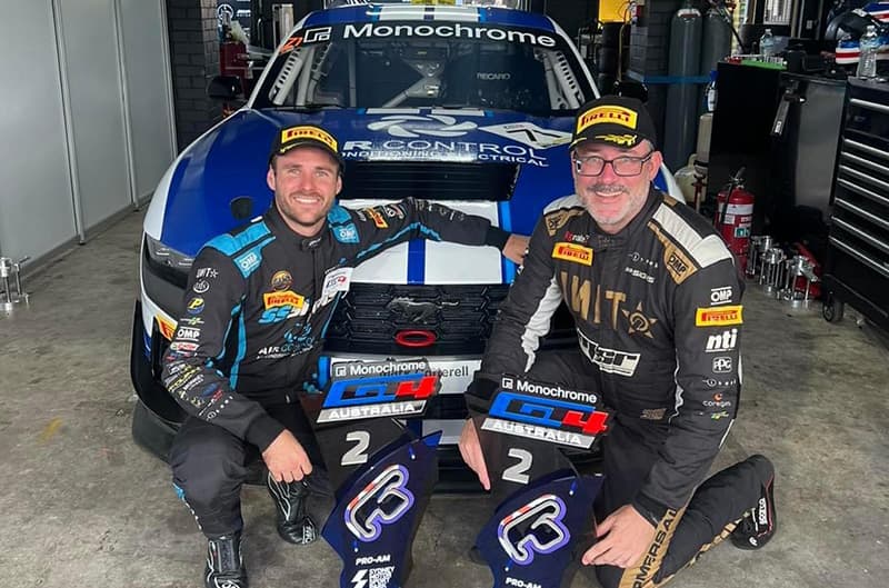 Two drivers posed in front of their Mustang GT4 in garage